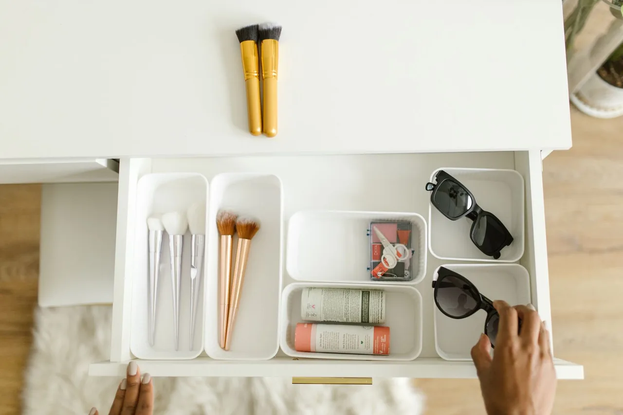 Drawer organizer trays separating sunglasses, makeup brushes and toiletries