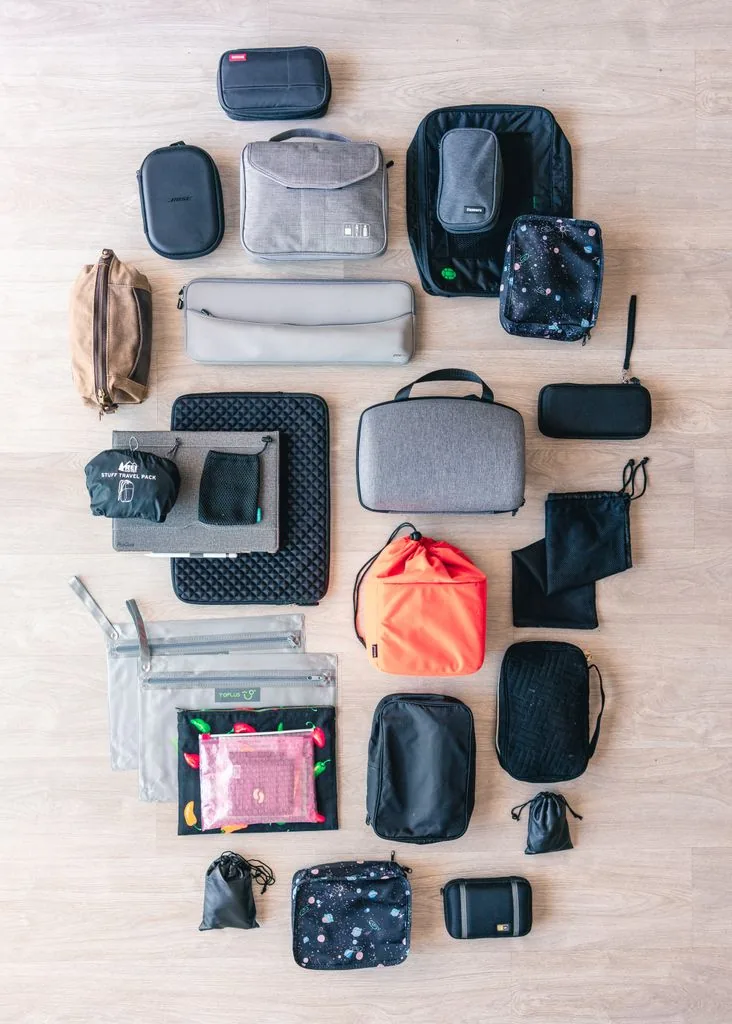 Travel packing bags and zippered pouches arranged by size on a wooden floor